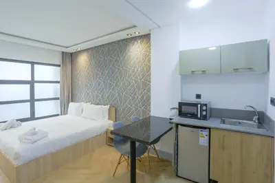 a small room with a bed and a desk with a microwave at Résidence Marie Césaire - Maarif in Casablanca