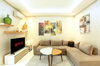 a living room with a couch and a tv at Résidence Sheren - Maarif in Casablanca
