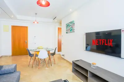a living room with a table and chairs and a tv at Résidence Liberté in Casablanca
