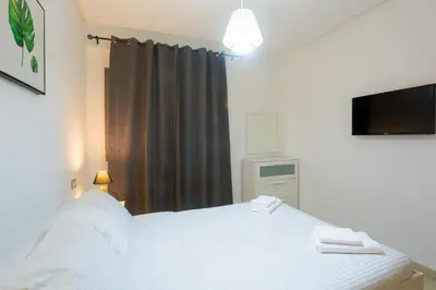 a bedroom with a white bed and a television at Résidence Liberté in Casablanca