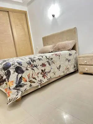 a bed with a flowered bedspread on it in a room at Appartement Moderne à OlaBlanca2 in Sidi Rahal