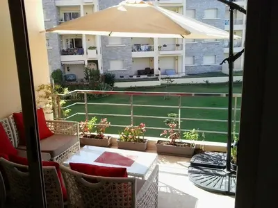 a balcony with a table and an umbrella at Appartement Bella Vista in Bouznika