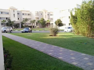 a sidewalk in a park with cars parked in a parking lot at Appartement Bella Vista in Bouznika