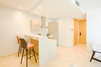 a kitchen with white walls and chairs and a counter at Résidence de Nice in Casablanca