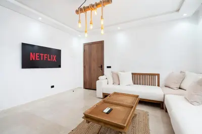 a living room with a white couch and a table at Studio Cosy Proche Gares & Mosqué Hassan II in Casablanca