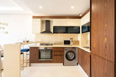 a kitchen with wooden cabinets and a washer and dryer at Charming & Airy Flat - Perfect for Relaxation in Casablanca