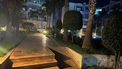 a walkway in front of a building at night at Best appartement pools view at Mansouria in Mohammedia