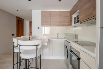 a kitchen with white counters and bar stools at 1 Bedroom with Terrace Casablanca City Center in Casablanca