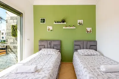 two beds in a room with a green wall at 4 min à pied de la Plage, 3 BR, Piscine, Parking in Skhirat