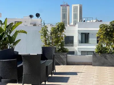 a patio with tables and chairs on top of a building at Cozy Studio à Palmier avec Roof top et Parking in Casablanca