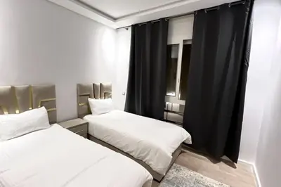 two beds in a room with black curtains at N9 Appartement pied sur mer, La Corniche Rabat in Rabat