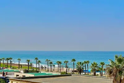 a view of the beach from a resort with palm trees at N9 Appartement pied sur mer, La Corniche Rabat in Rabat