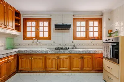 a large kitchen with wooden cabinets and a sink at Spacious Harhoura Villa: Perfect for Families (5min to Beach) in El Harhoura
