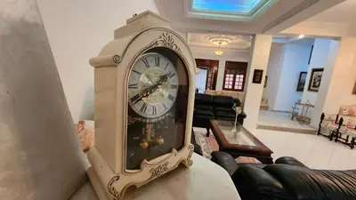 a grandfather clock sitting on a table in a living room at Spacious Harhoura Villa: Perfect for Families (5min to Beach) in El Harhoura