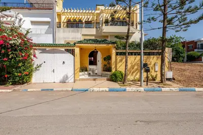 a yellow house with a gate and a white garage at Spacious Harhoura Villa: Perfect for Families (5min to Beach) in El Harhoura