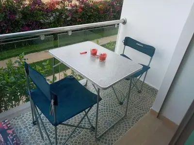 a table and two chairs with red cups on a balcony at Cocon cozy à Mansouria Mer, piscines et nature in Mansouria