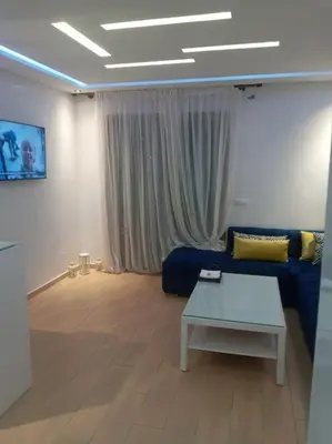 a living room with a blue couch and a table at Cocon cozy à Mansouria Mer, piscines et nature in Mansouria
