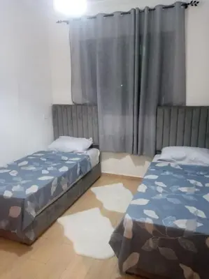 a bedroom with two beds and a window with curtains at Cocon cozy à Mansouria Mer, piscines et nature in Mansouria