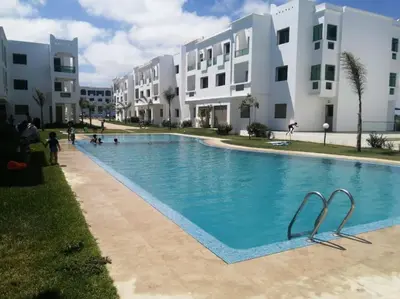 a large swimming pool in front of some buildings at Cocon cozy à Mansouria Mer, piscines et nature in Mansouria
