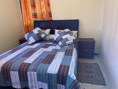 a bedroom with a bed with pillows and a night stand at Appartement oulfa in Casablanca