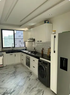 a kitchen with white cabinets and a washer and dryer at Chambre à Agdal Rabat dans un appartement partagé in Rabat