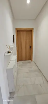 a room with a wooden door and a white kitchen at Cosy & Confort Studio près de l'aéroport in Nouaceur