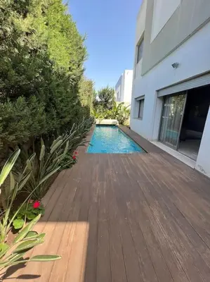 a wooden walkway leading to a swimming pool next to a building at Villa de Luxe piscine privée in Casablanca