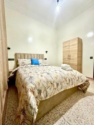a bedroom with a large bed and a wooden cabinet at Jolie Appt à skhirat 5min de la plage par voiture in Skhirat