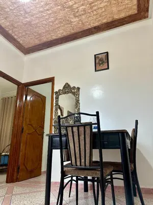 a dining room table with two chairs and a mirror at Jolie Appt à skhirat 5min de la plage par voiture in Skhirat