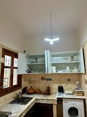 a kitchen with white cabinets and a washing machine at Jolie Appt à skhirat 5min de la plage par voiture in Skhirat