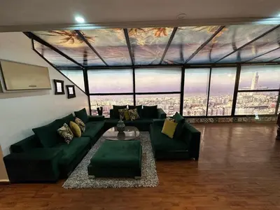 a living room with a green couch and a large window at Appartement loft de luxe dans un quartier Art Déco en plein centre de Casablanca in Casablanca