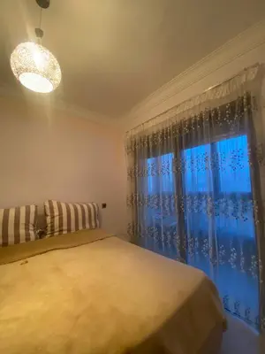 a bedroom with a bed and a large window at Appartement sur SIDI Rahal in Casablanca