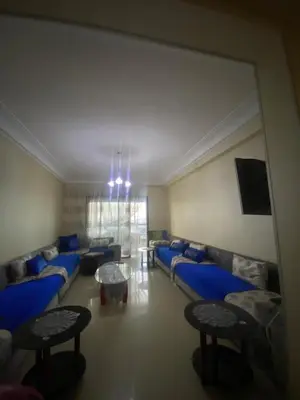 a living room with blue couches and a table at Appartement sur SIDI Rahal in Casablanca