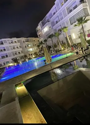 a swimming pool in a city at night with buildings at Résidence Mansbay Rosa, Mohammedia in Mohammedia
