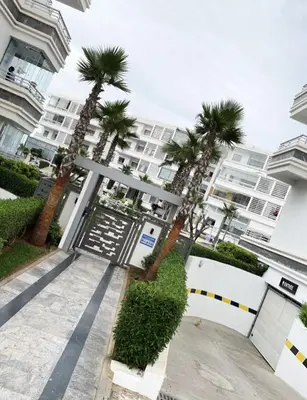 a gate with palm trees in front of a building at Résidence Mansbay Rosa, Mohammedia in Mohammedia