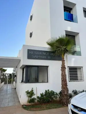 a building with a palm tree in front of it at ZS house harhoura vue sur piscine in Temara