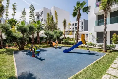a playground in front of a building with palm trees at ZS house harhoura vue sur piscine in Temara