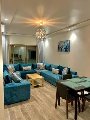a living room with a blue couch and a table at Heaven Beach SIDI RAHAL in Sidi Rahal