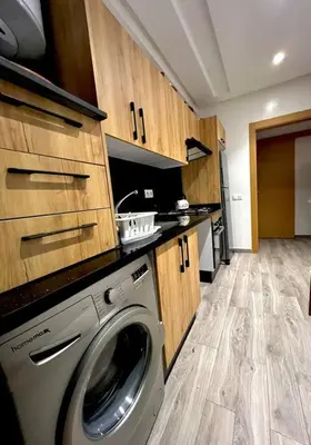 a washing machine in a kitchen with wooden cabinets at Heaven Beach SIDI RAHAL in Sidi Rahal