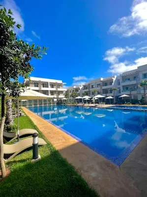 a large swimming pool with a bench next to a building at Heaven Beach SIDI RAHAL in Sidi Rahal
