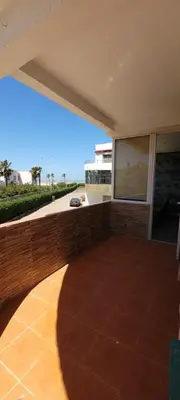 a patio with a brick wall and a large screen at Bel appartement avec vue sur mer Sidi Rahal in Sidi Rahal