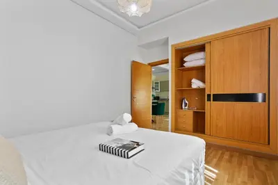 a bedroom with a white bed and a wooden cabinet at Serene One Bed Oasis in the Heart Of The Medina in Les Camps