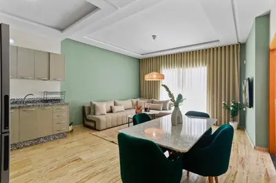 a kitchen and a living room with a table and chairs at Serene One Bed Oasis in the Heart Of The Medina in Les Camps