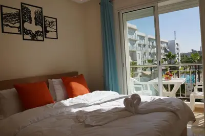 a bed in a bedroom with a view of a balcony at Jolie Appartement 2 chambres / vue piscine in Bouznika