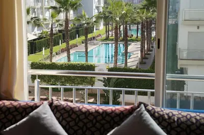 a couch in front of a window with a view of a pool at Jolie Appartement 2 chambres / vue piscine in Bouznika