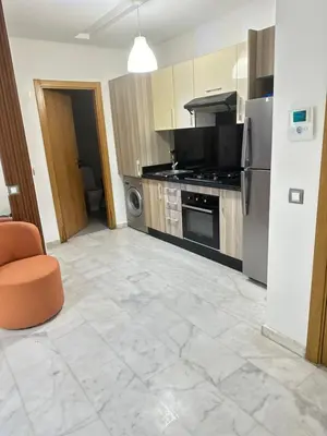 a kitchen with stainless steel appliances and an orange chair at Appartement confortable au corniche in Mohammedia