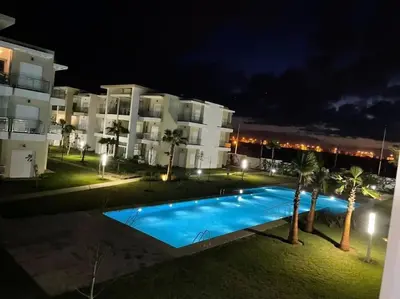 a swimming pool in front of a building at night at CASA BAY BEACH OMK 3 in Sidi Rahal