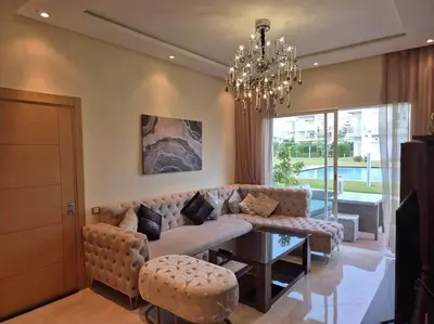 a living room with a couch and a chandelier at CASA BAY BEACH OMK 3 in Sidi Rahal