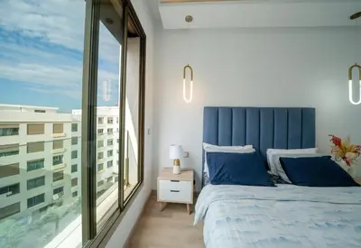 a bedroom with a blue bed and a large window at Two bedrooms sunny appartement in ain diab in Casablanca