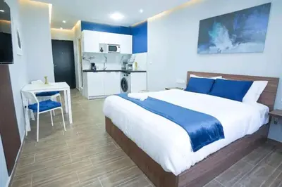 a bedroom with a bed and a table and a kitchen at Luxury Studio, Coeur de l'Agdal in Rabat